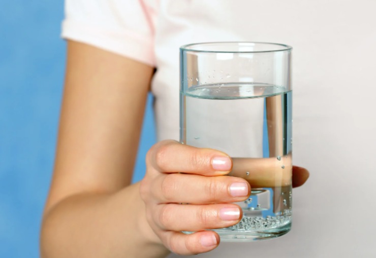 persona con in mano un bicchiere di acqua
