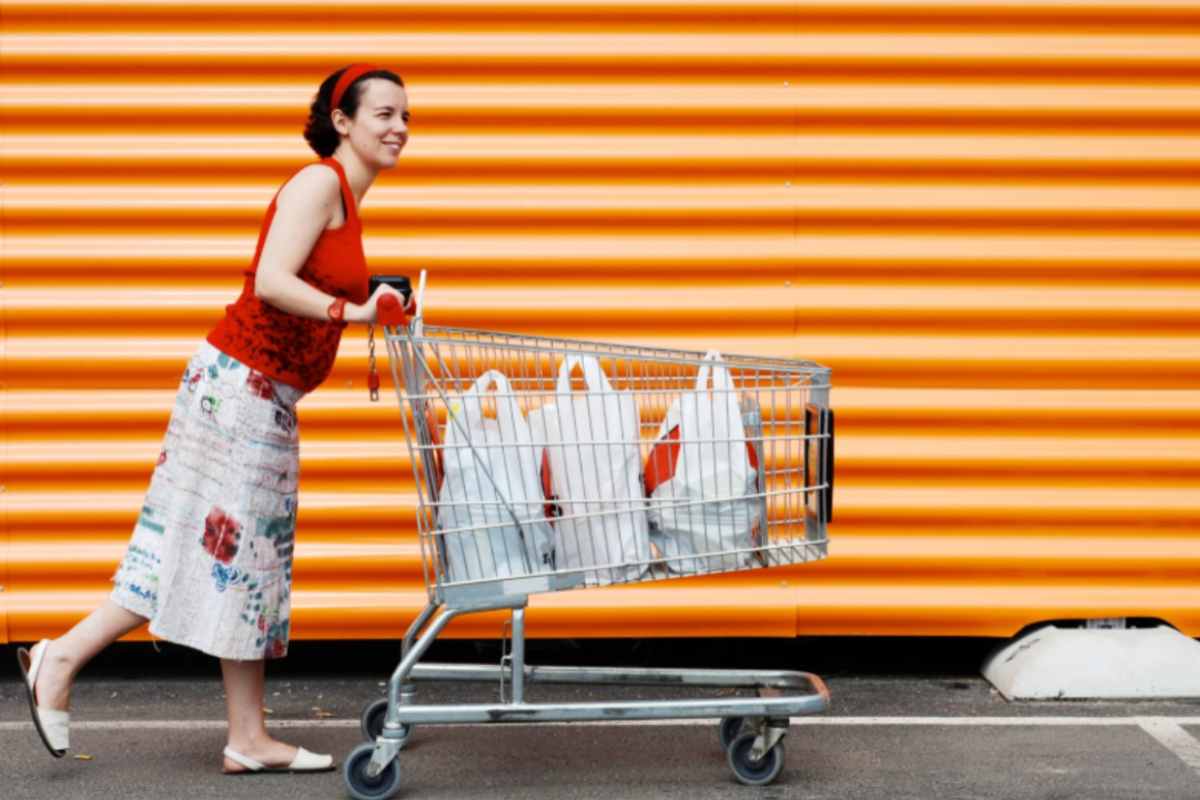 donna che spinge il carrello della spesa pieno di sacchetti