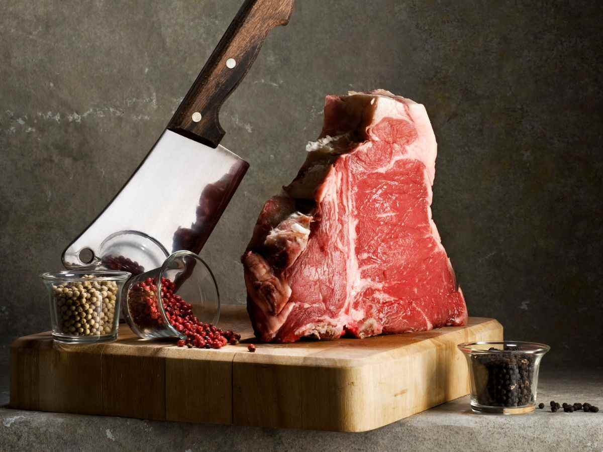 una fiorentina su un tagliere insieme a una mannaia