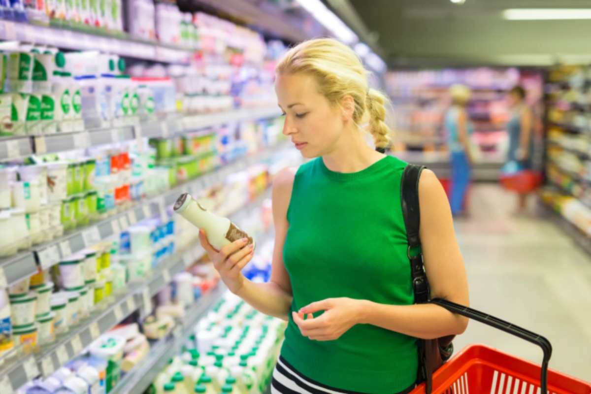 donna che fa la spesa al supermercato con il cestino attaccato al braccio