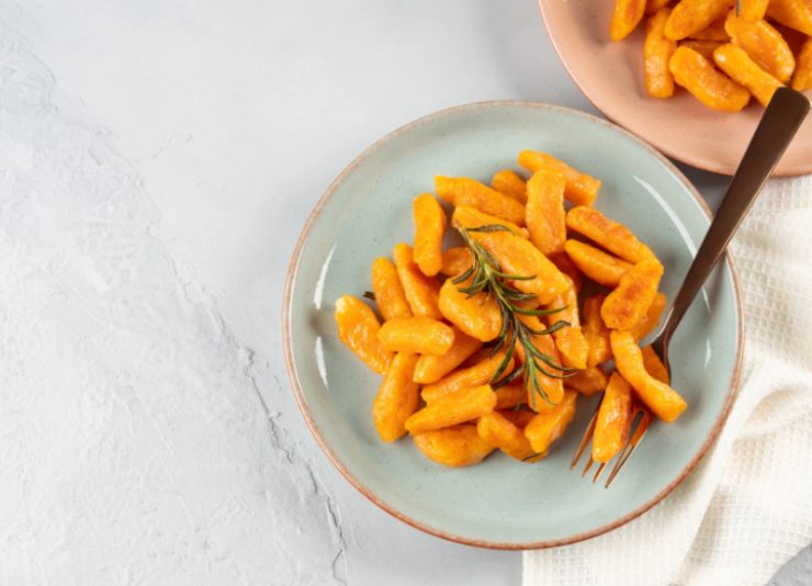 gnocchi di zucca dentro ad un piatto con sopra del rosmarino
