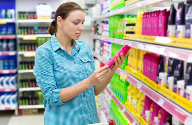 donna al supermercato con in mano un flacone rosa