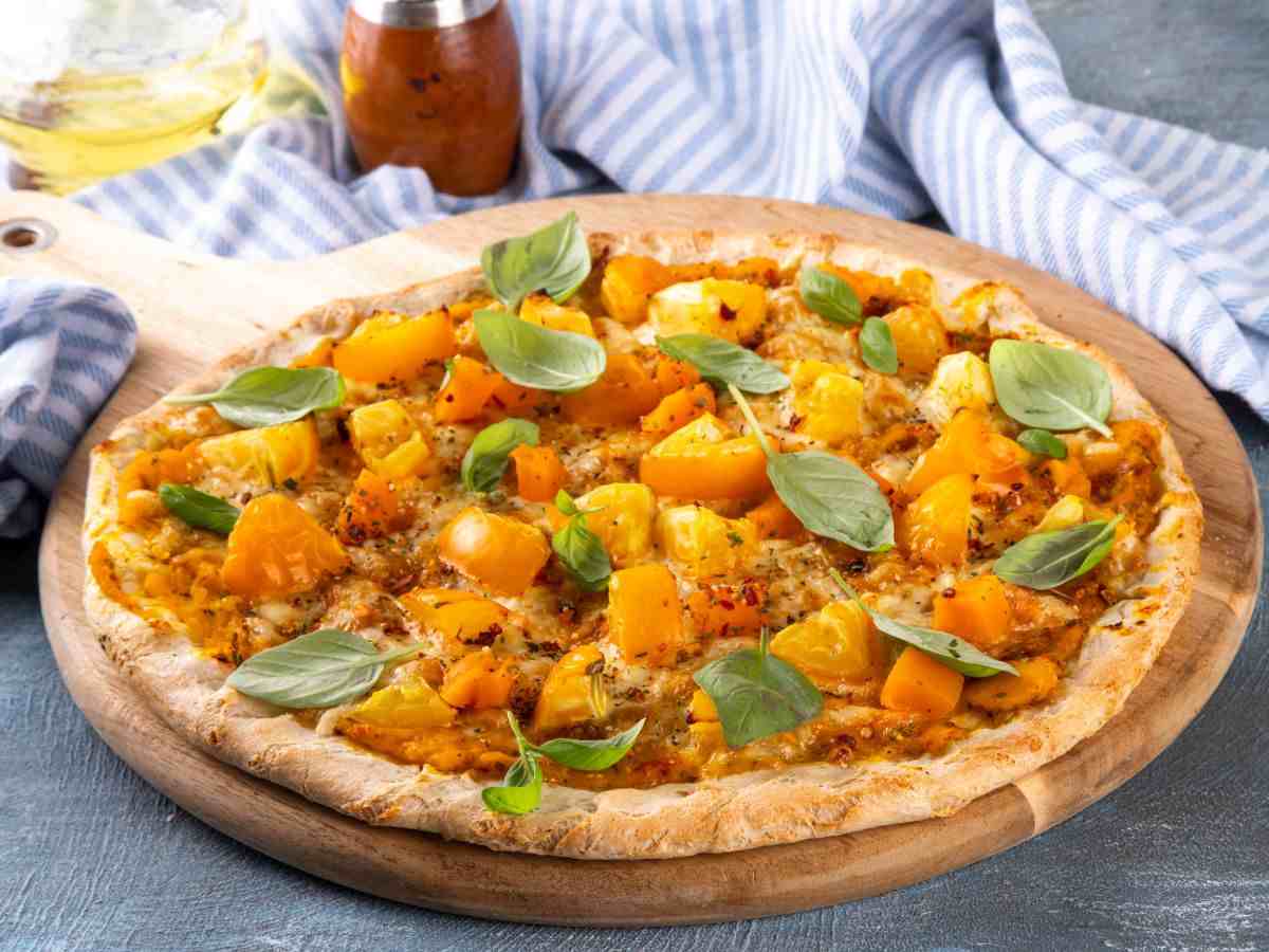 una pizza condita con zucca e pomodorini