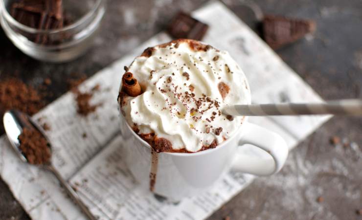 tazza di cioccolata calda con panna con cannuccia e cucchiaino