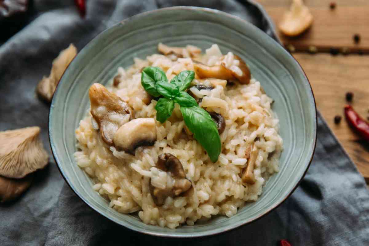 Piatto con risotto ai funghi e foglie di basilico