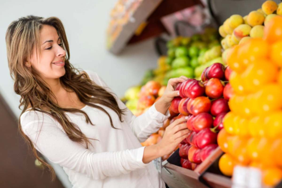 donna al supermercato che sceglie la frutta