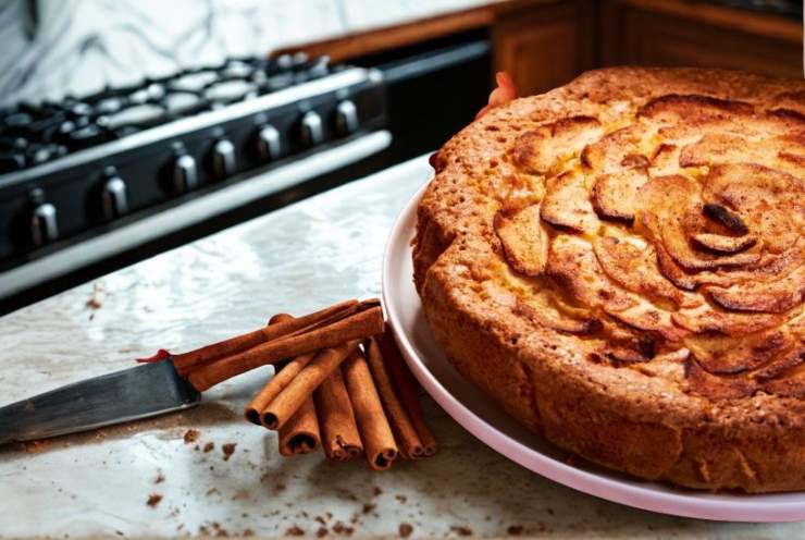 torta di mele sul tavolo della cucina con accanto un coltello e della cannella
