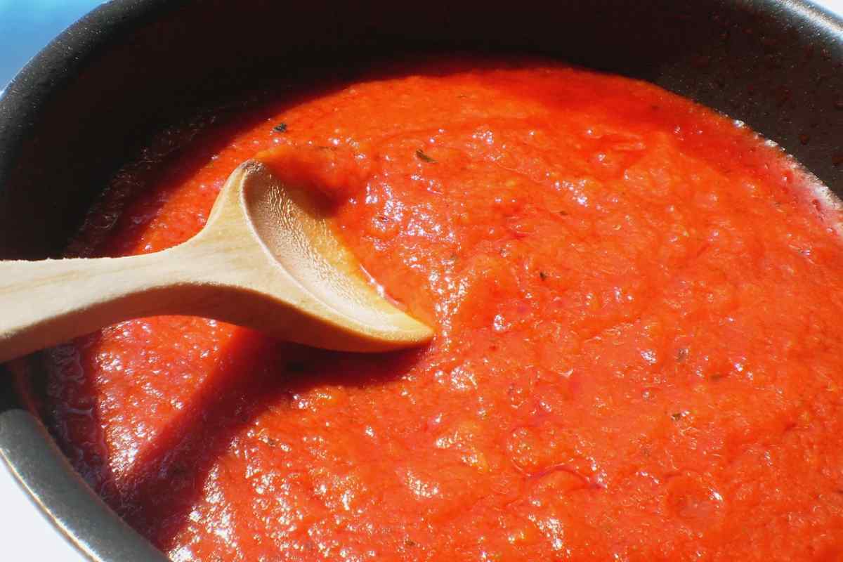 Sugo di pomodoro in una padella con mestolo in legno