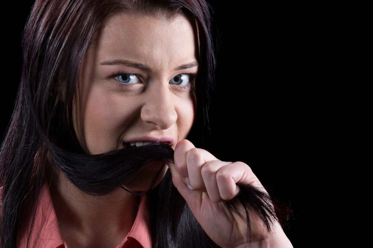 ragazza con una ciocca di capelli in bocca